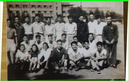 照片1：1951年春，北大工学院电机系二年级部分同学摄于北大民主广场，背景为红楼对面的灰楼(当时女生宿舍)。照片中有箭头者是作者。